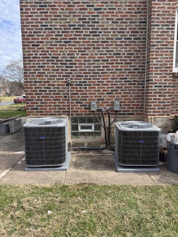 Two outdoor AC units side by side behind a brick building